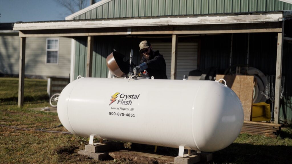 man filling propane tank outside of a house